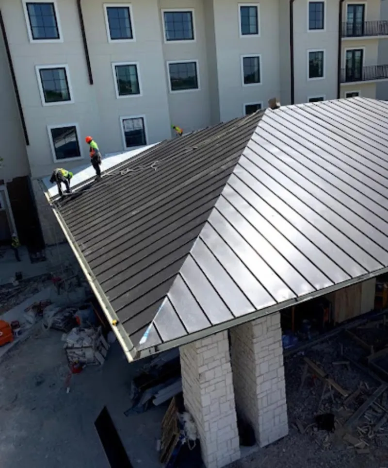 Crew installing standing seam metal roof panels on a commercial project in Mayville